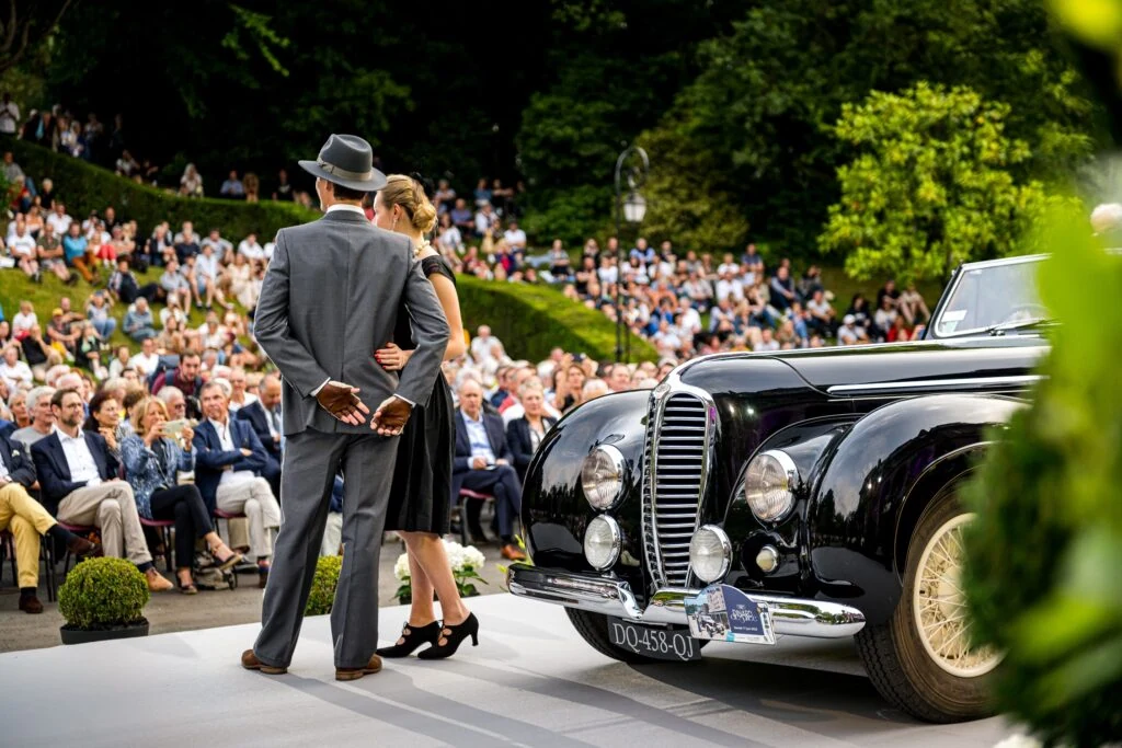 Guests beside a classic convertible at an outdoor concours event